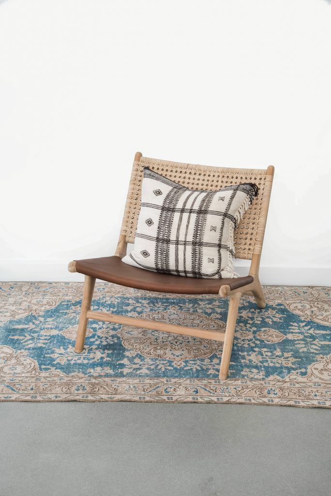 styled leather and rattan lounge chair with an accent pillow