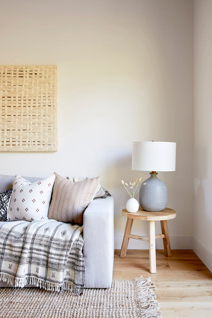 Styled Vintage Elmwood Side Table - Round in a neutral space with Hmong pillows and a Bhujodi blanket. - Saffron and Poe