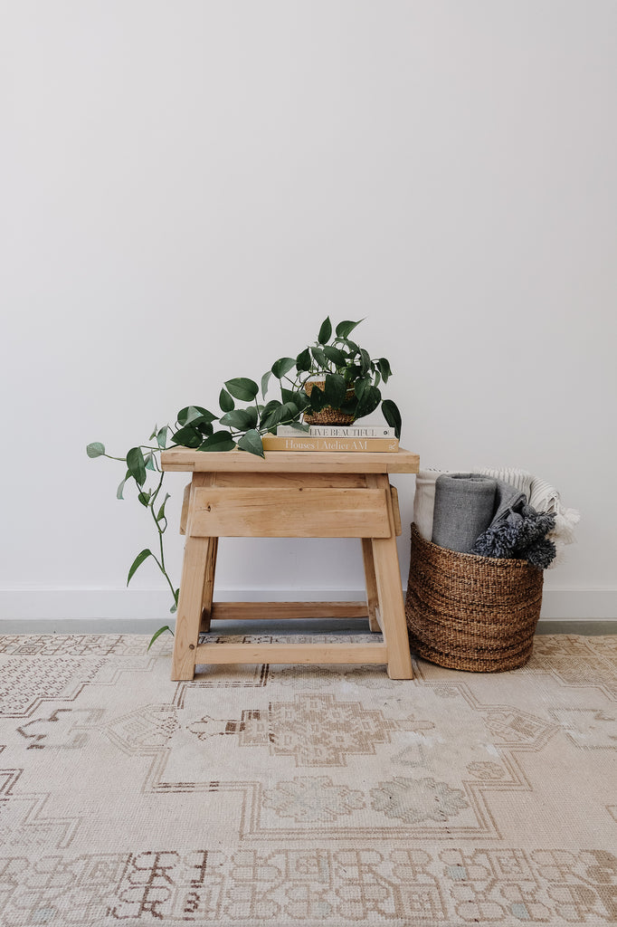 Styled view of Vintage Cedar End Table with books and a plant on a Vintage Turkish Rug. - Saffron + Poe