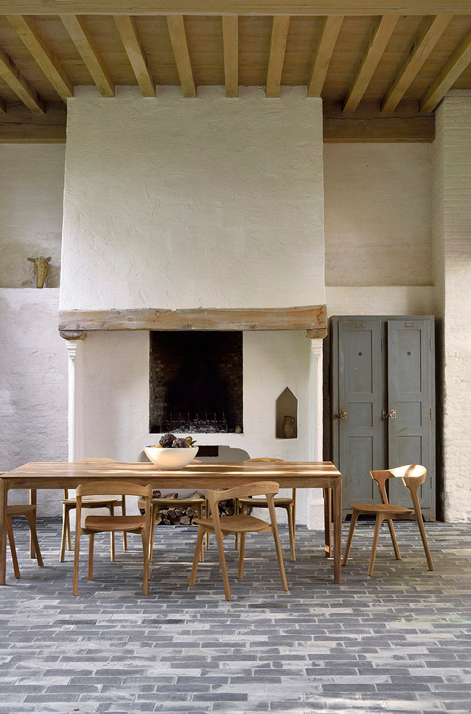 Teak Bok Extendable Dining Table and Chairs in European inspired dining room with plaster fireplace and paver floors, exposed beams on ceiling. - Saffron and Poe, Ethnicraft