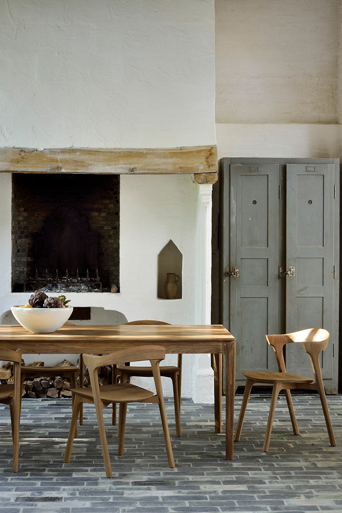 Detail vignette of Teak Bok Extendable Dining Table and Chairs in European inspired dining room with plaster fireplace and paver floors. - Saffron and Poe, Ethnicraft