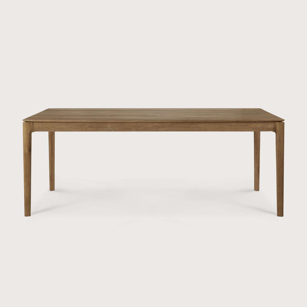 Bok Dining Table made of natural teak with contoured frame and floating top in a bright dining room