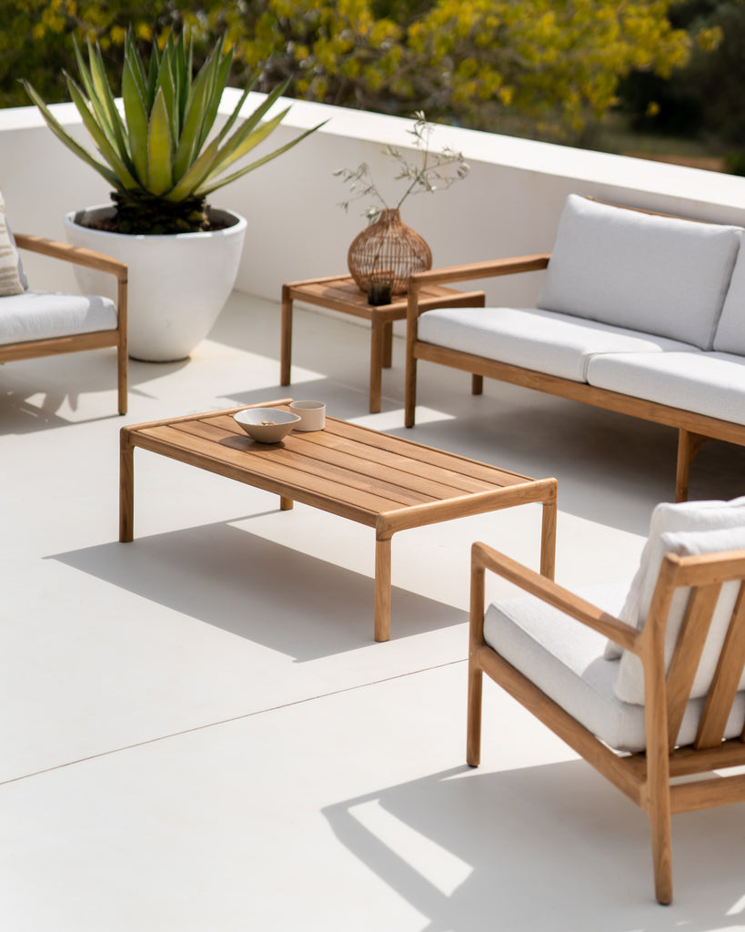 Slatted Teak Outdoor Jack Coffee Table and Jack Outdoor Lounge Chairs on an outdoor patio, styled with a small ceramic bowl on top. - Saffron and Poe, Ethnicraft