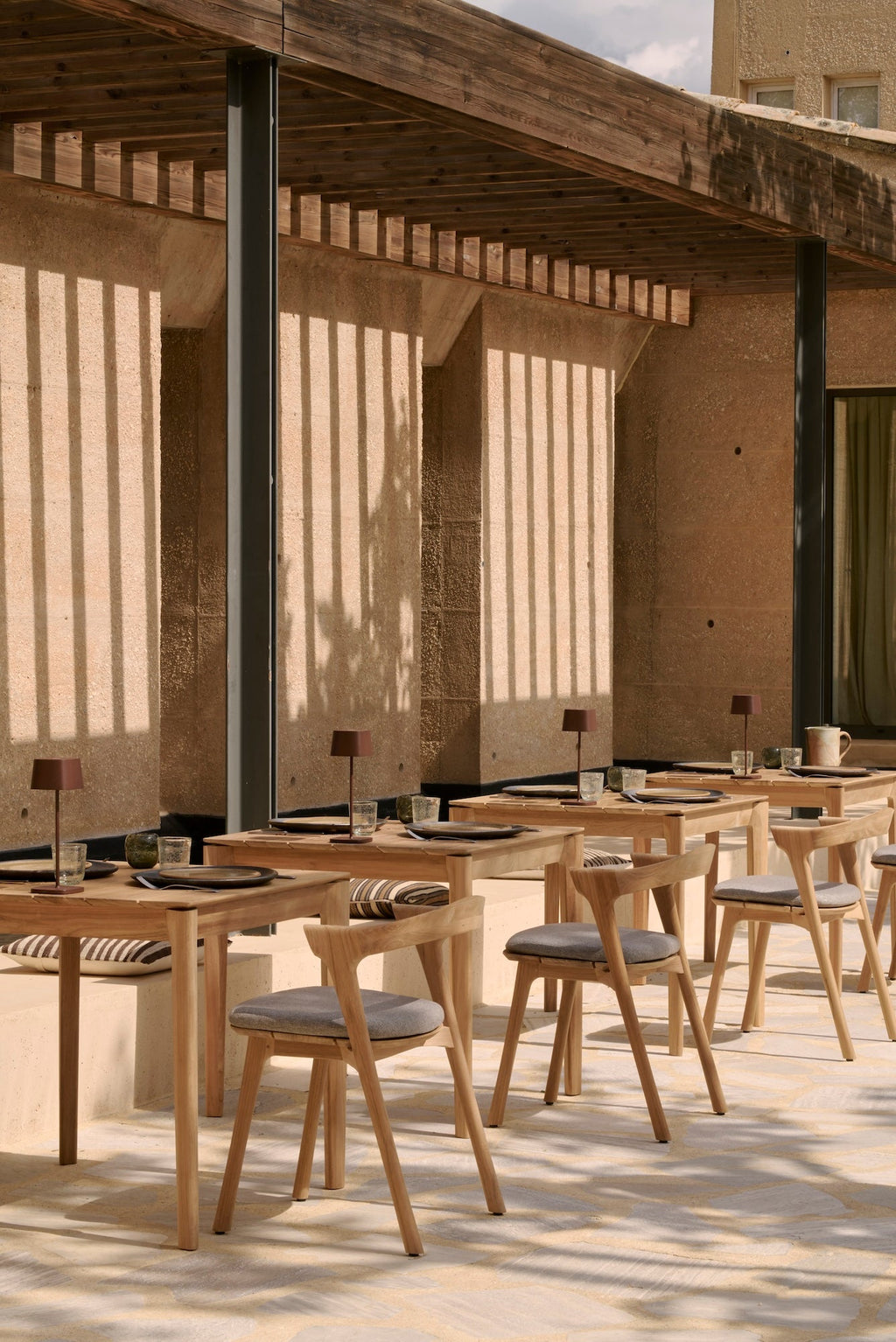 Bok Outdoor Dining Table made of sculptural teak with floating slatted tabletop in a modern outdoor setting