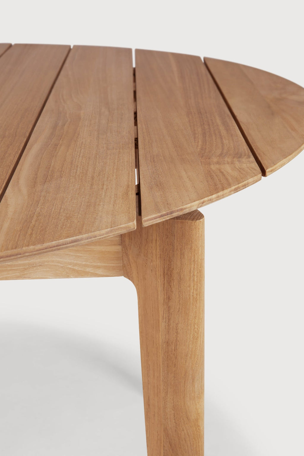 Bok Circle Outdoor Dining Table with teak slatted top and sculptural frame in outdoor setting