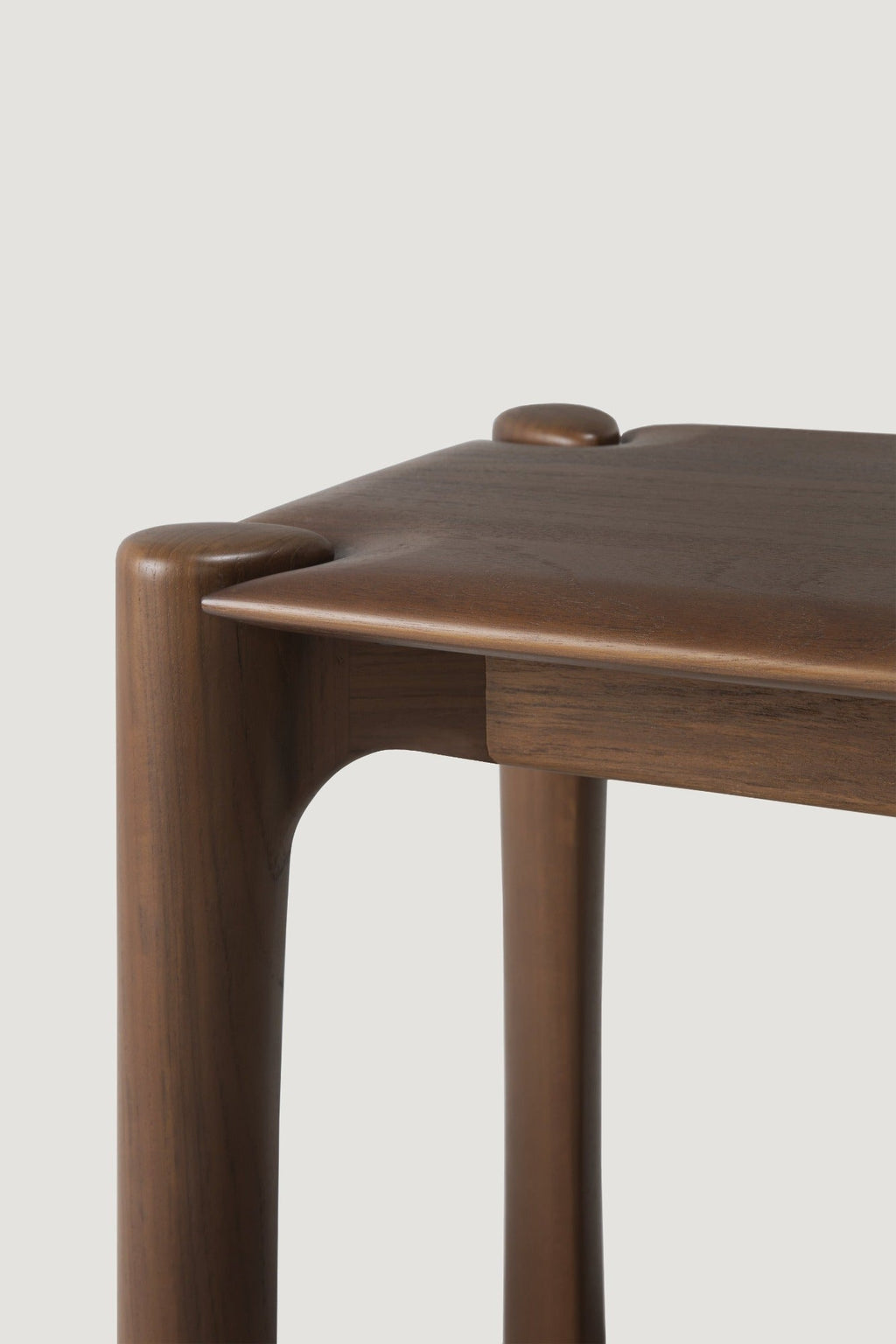 PI Bench in dark teak with sculpted base and curved edges, handcrafted solid teak furniture