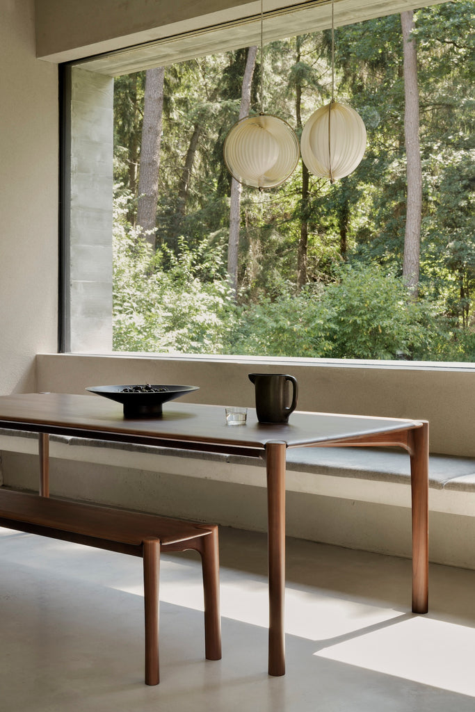 Dark Teak PI Bench and PI Dining Table in dining room with lantern light fixture pendants and view of woods outside window.  - Saffron and Poe, Ethnicraft