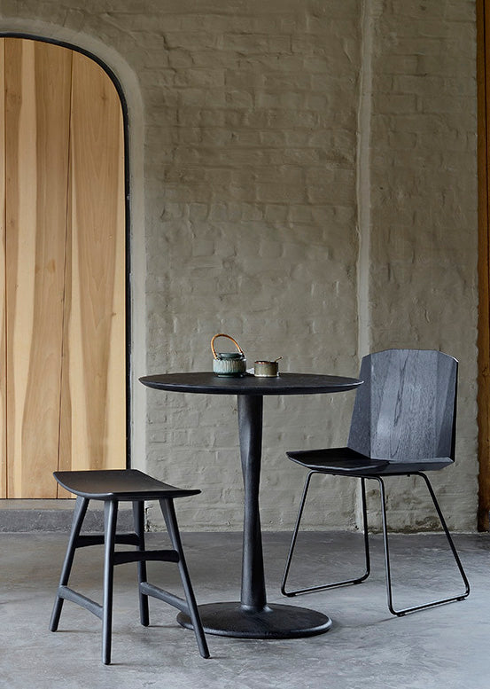 Black Oak Torsion Dining Table in bright dining room with large windows and concrete floor. - Saffron and Poe, Ethnicraft