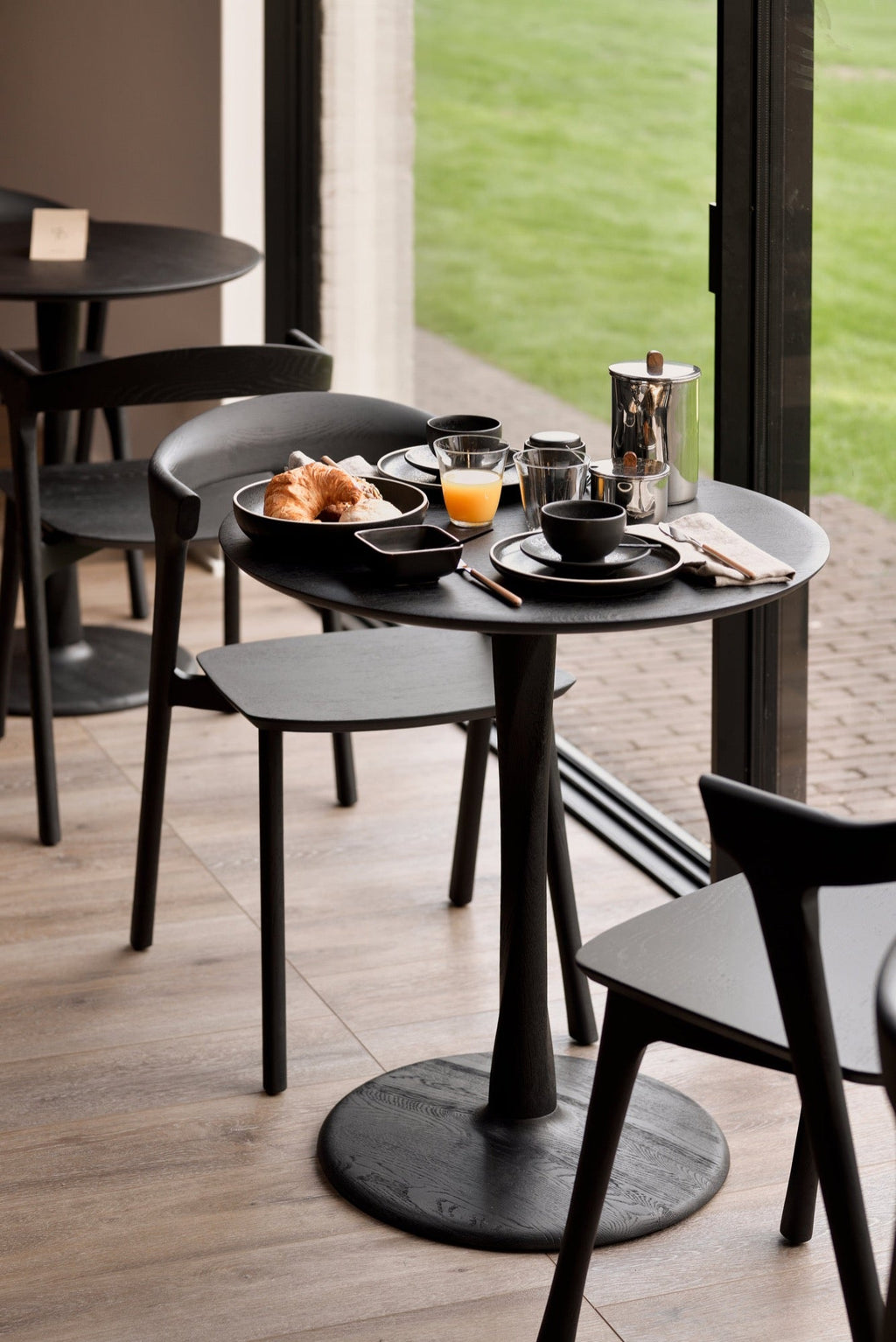 Black oak Torsion Dining Table with round top and sculptural twisted pedestal base