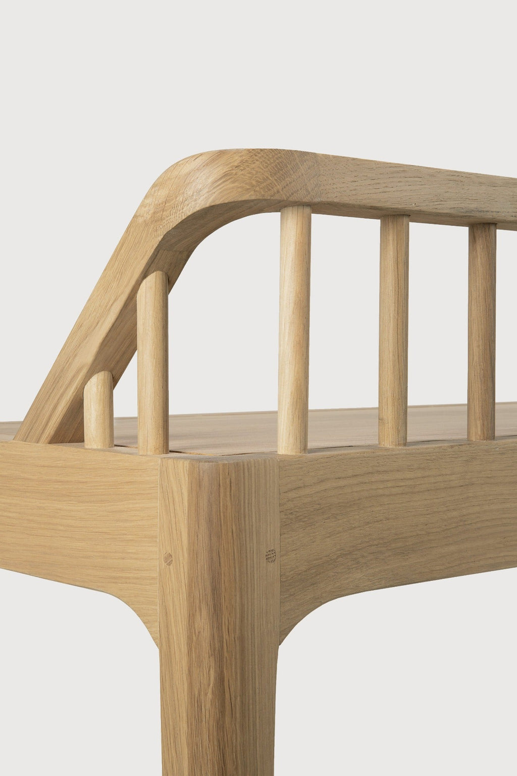 White oak spindle bench with low spoked back and spacious seat in a coastal modern style