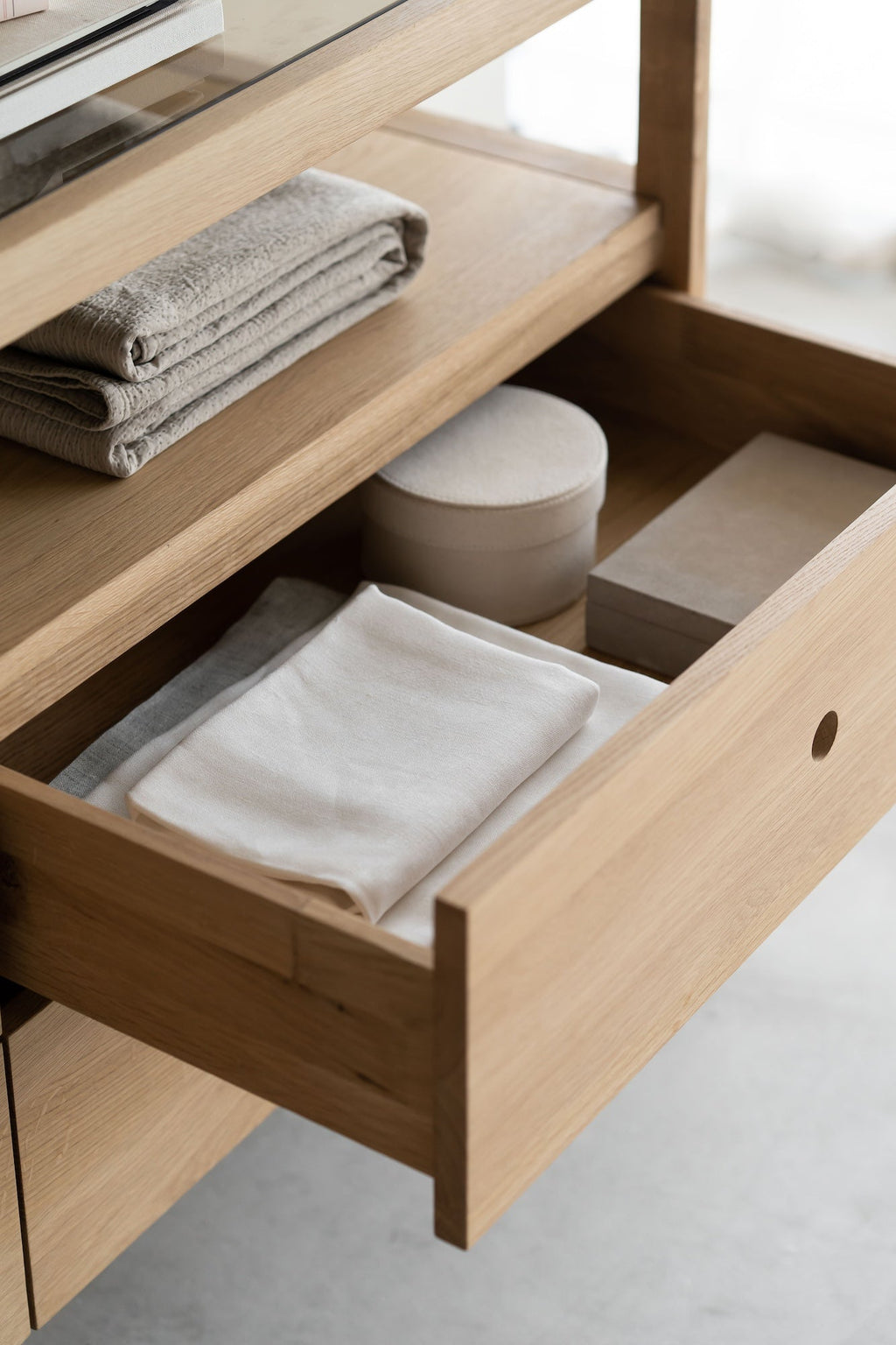 Spindle Dresser in oak with four drawers, open shelf, and glass top, showcasing a minimalist coastal California design.