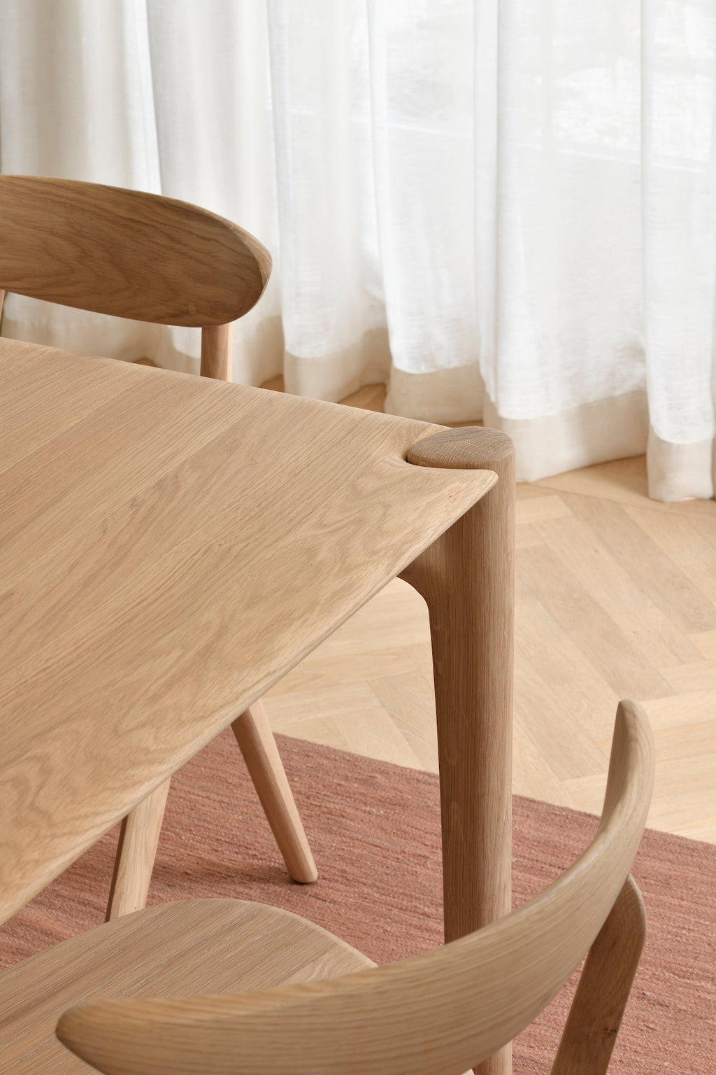 PI Dining Table in white oak with sculpted base and curved edges, featuring a polished organic finish