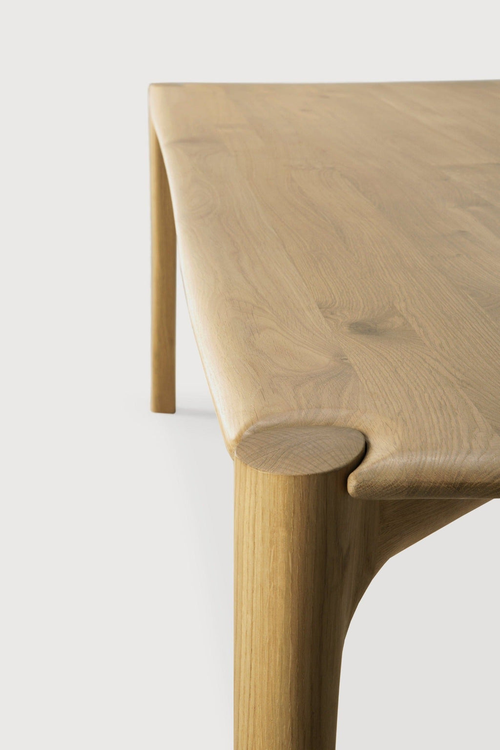 PI Dining Table in white oak with sculpted base and curved edges, showcasing a modern organic finish