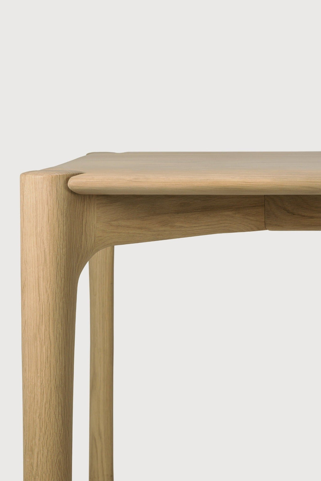 PI Dining Table in white oak with sculpted base and curved edges, showcasing a modern organic finish