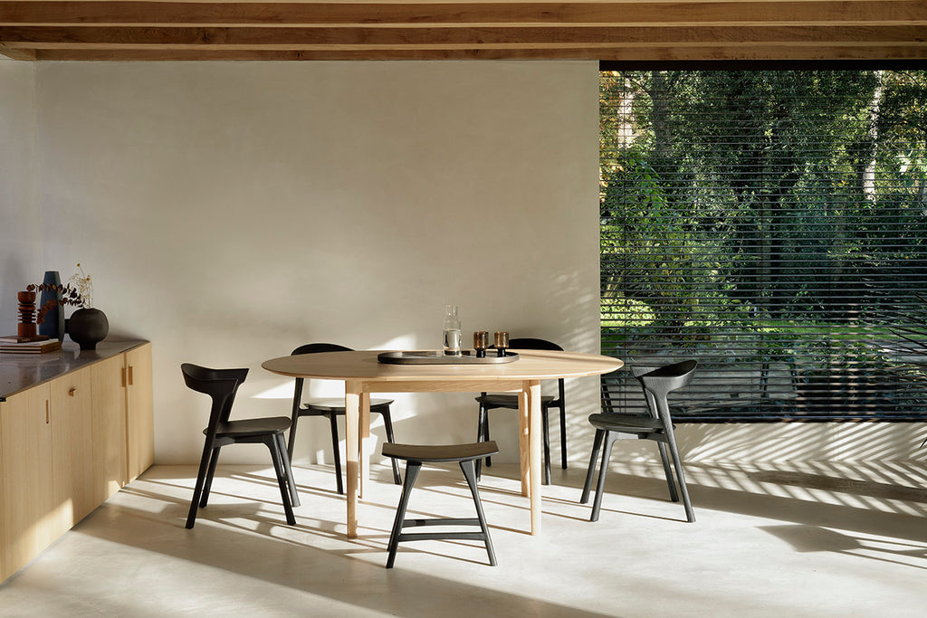 Oak Bok Round Extendable Dining Table and Black Oak Bok dining chairs in dining room with plaster walls, exposed beam ceiling and sideboard. - Saffron and Poe, Ethnicraft