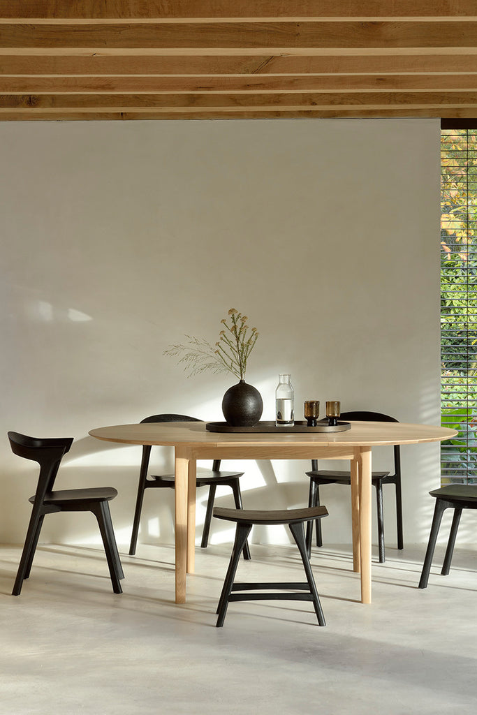 Oak Bok Round Extendable Dining Table and Black Oak Bok dining chairs in dining room with plaster walls, exposed beam ceiling. - Saffron and Poe, Ethnicraft