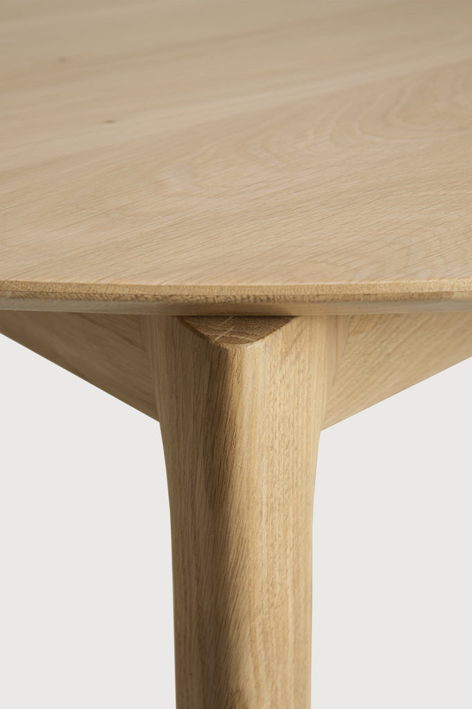 Oak Bok Round Extendable Dining Table close up detail with white background featuring floating table top and beautiful wood joinery. - Saffron and Poe, Ethnicraft