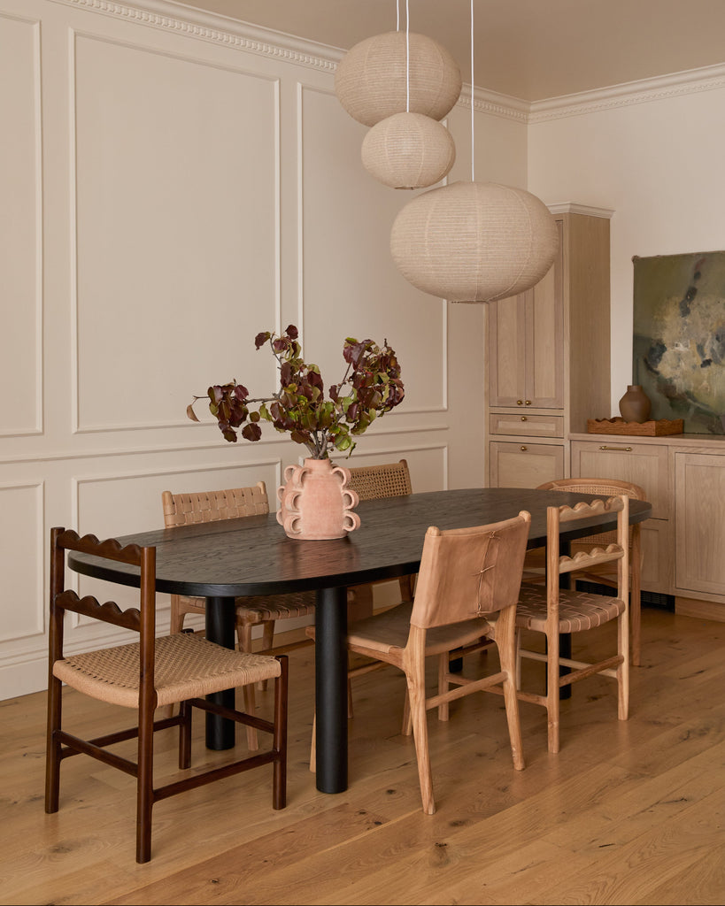 Aegean Scalloped Dining Chair in a dining room with a black table with other Saffron and Poe chairs around it. Saffron and Poe