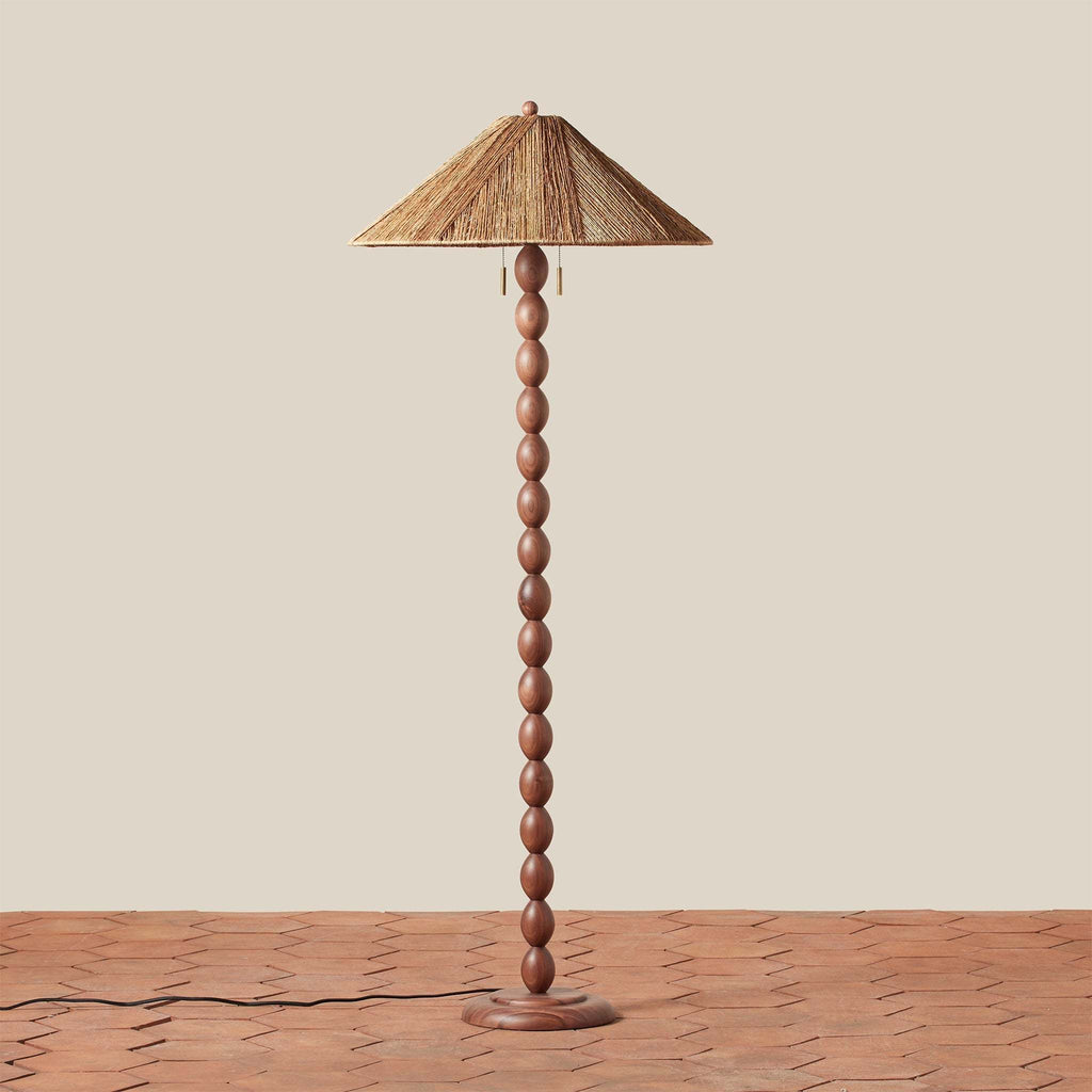 Wooden Alhambra floor lamp with a woven shade on a wooden surface and beige background