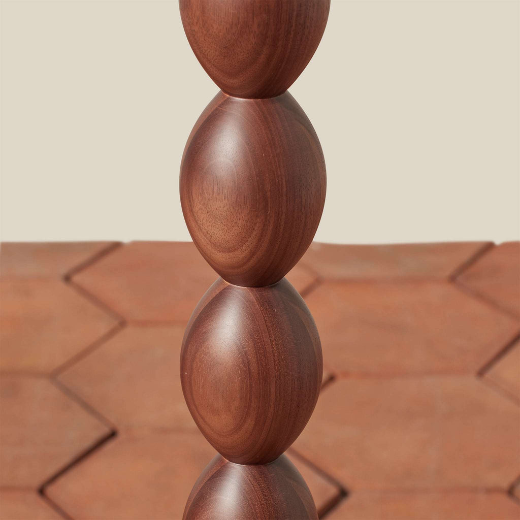 Stack of wooden spheres from the Alhambra Floor Lamp on a textured surface with a neutral background