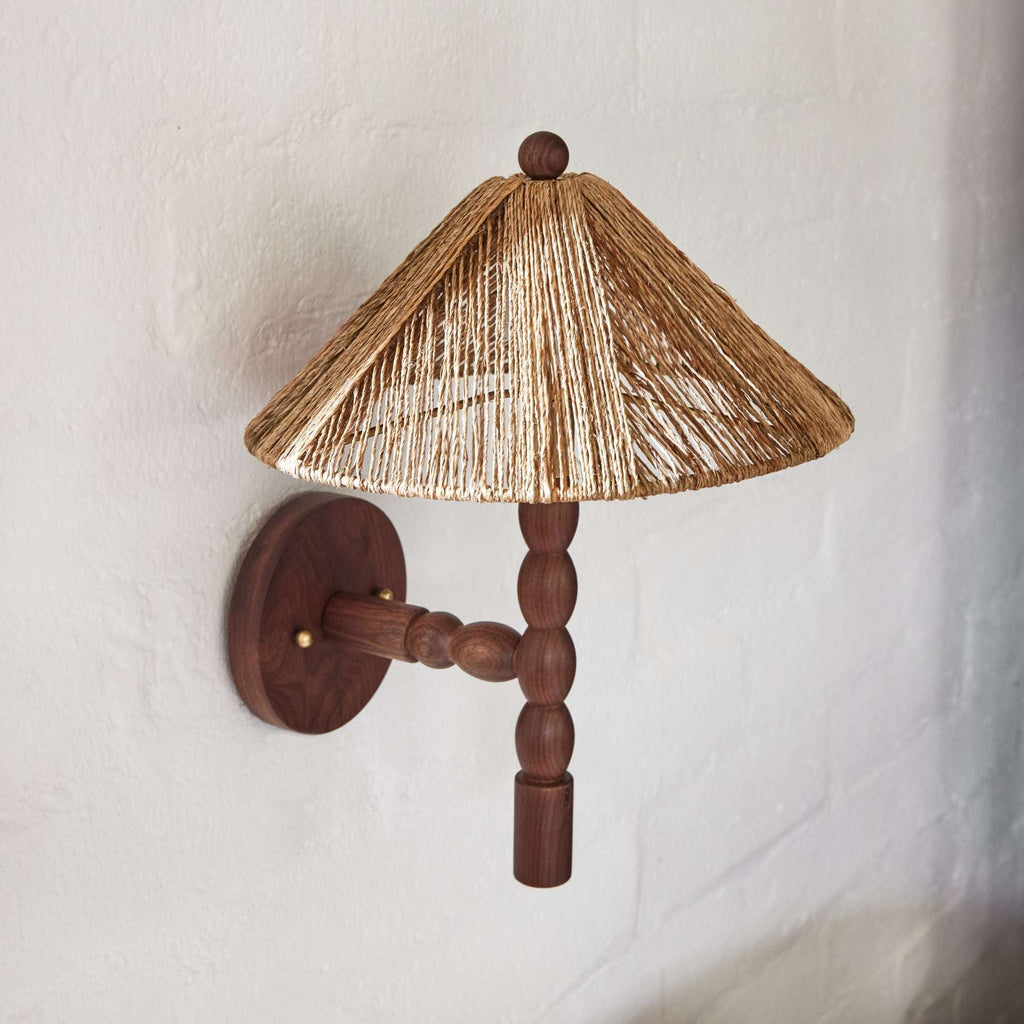 Wooden Alhambra wall sconce with a straw-like lampshade on a white wall.