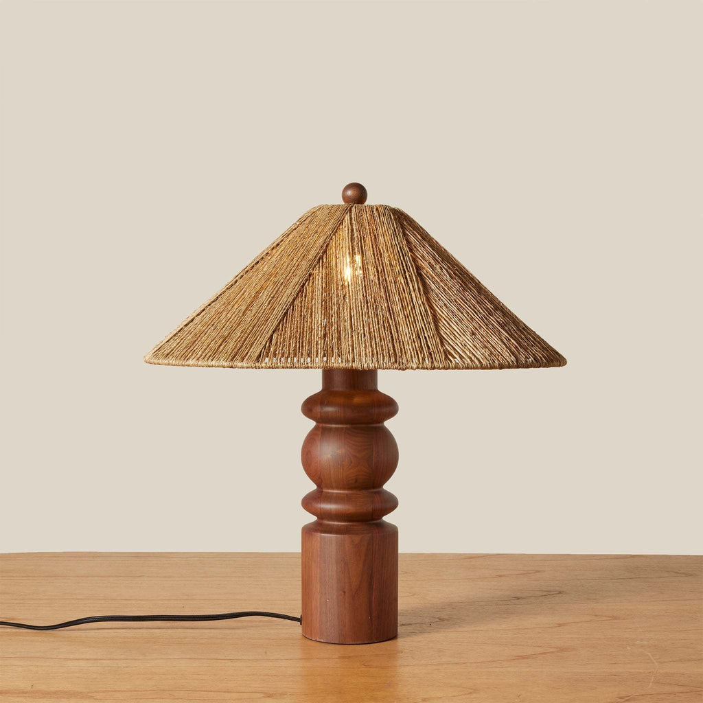 Wooden Alhambra table lamp with a wicker shade on a wooden surface.
