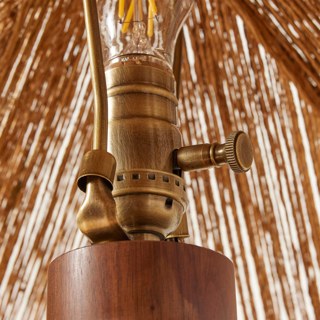 Close-up of a vintage-style lamp with wooden base and brass accents against a woven background.