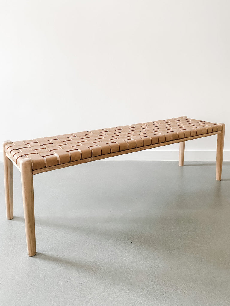 Angled view of 60" woven leather strap bench in beige against white background. Handcrafted in Bali. Teak wood and leather straps. - Saffron and Poe