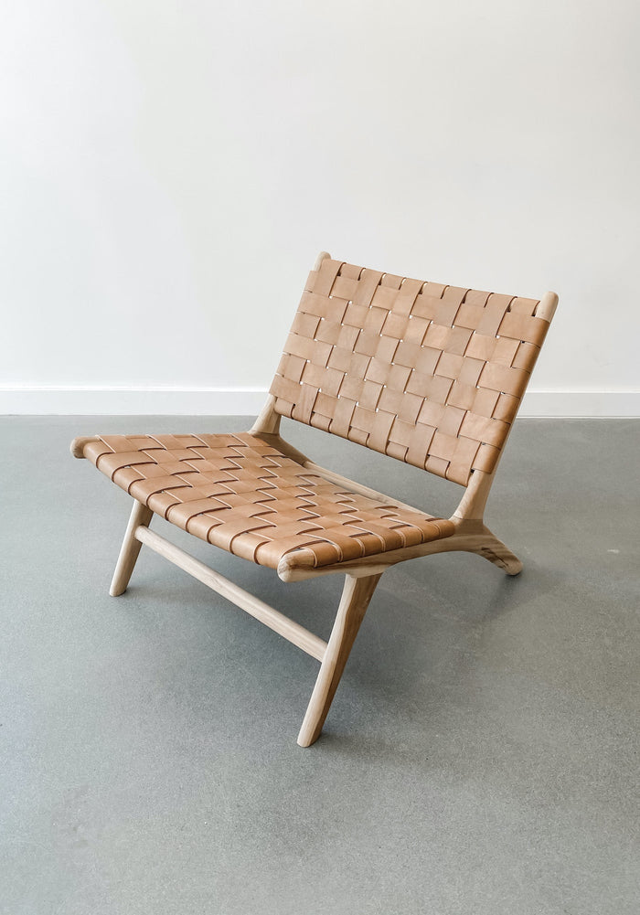 Angled view of Woven Leather Strap Lounge Chair in Beige against white background. Handcrafted in Bali. Teak wood and leather straps. - Saffron and Poe