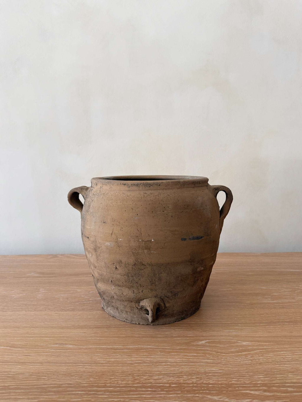 Antique clay pot with umber patina, handcrafted and used for fermenting rice wine, styled with greenery.