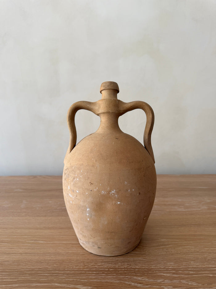 Antique Italian Vessel with handles on a wooden surface and neutral lime washed background. Saffron + Poe