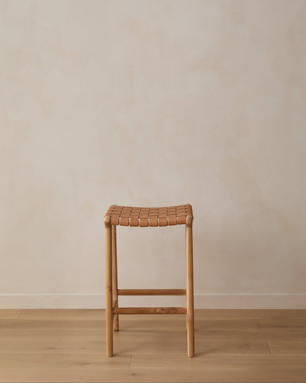 Backless woven leather counter stool in beige with carved teak frame and natural matte finish