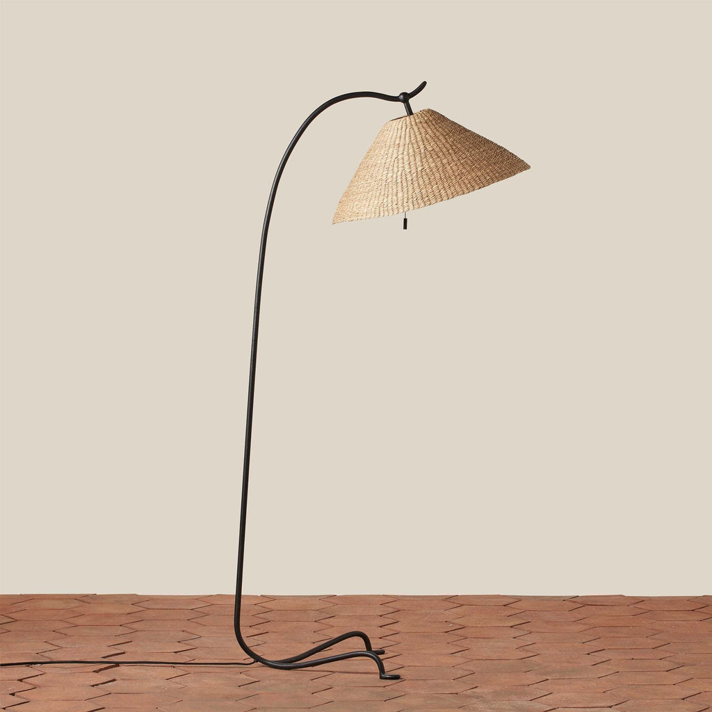 Bainbridge Floor lamp with wicker shade on a wooden floor against a beige wall