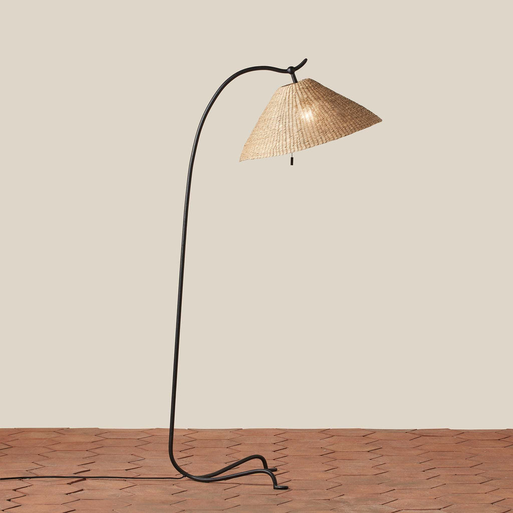 Bainbridge Floor lamp with wicker shade on a wooden floor against a beige wall