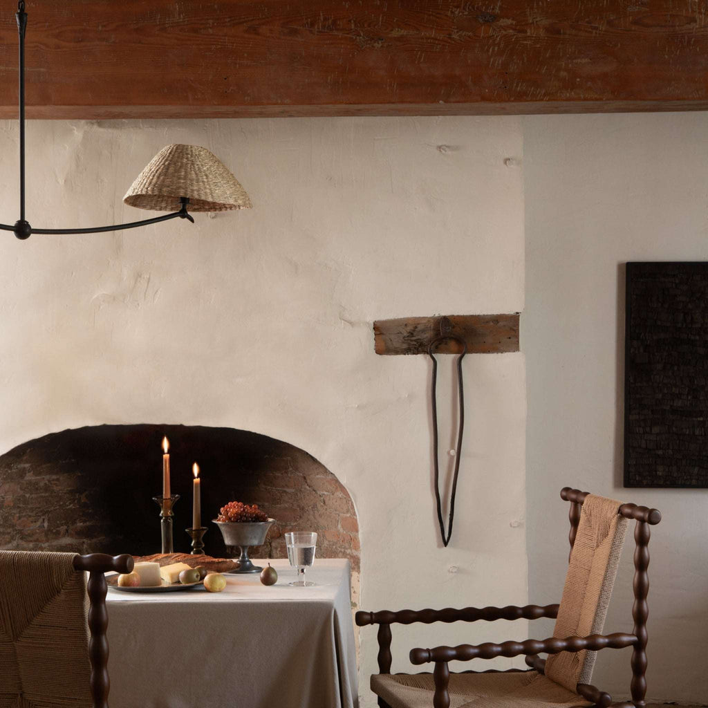 Dining room with rustic decor, including a fireplace, wooden chairs, a table set for a meal, and a Bainbridge linear pendant above