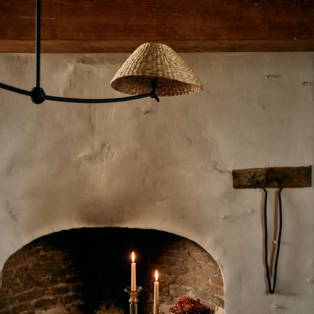 Woven Bainbridge linear pendant lampshade hanging above a fireplace with candles