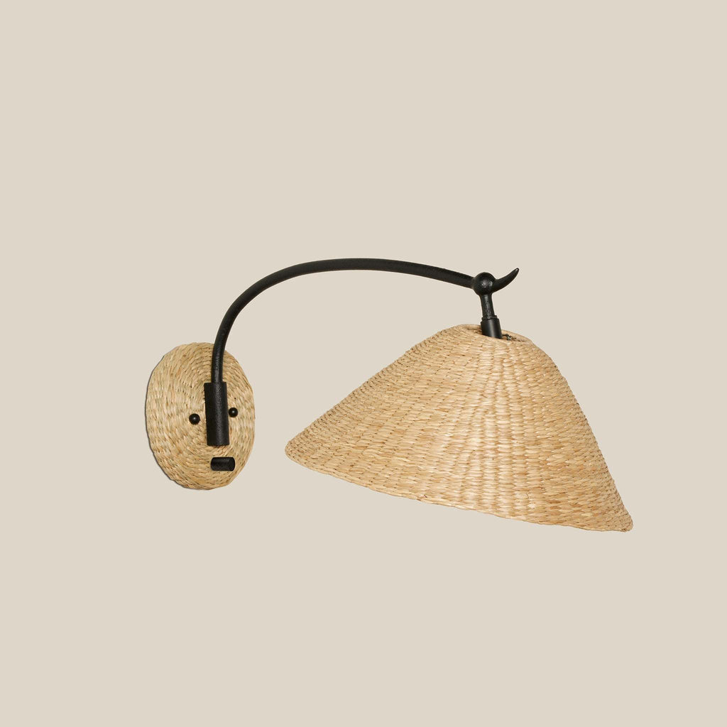 Woven seagrass Bainbridge oversized swing arm sconce with black metal arm on a beige background.