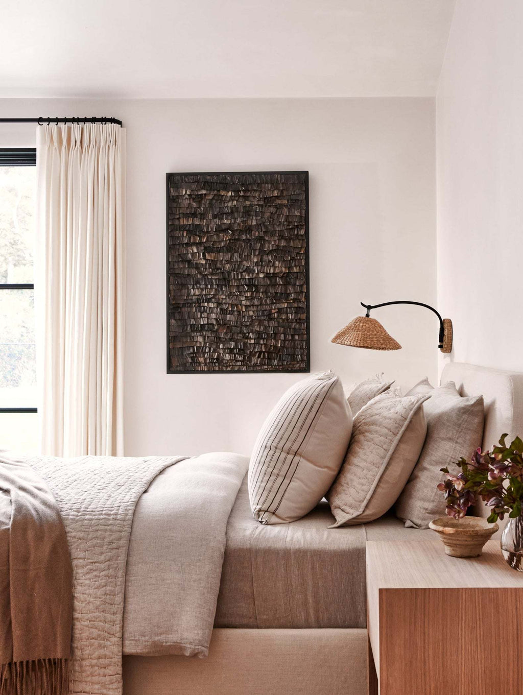Bainbridge sconce above a neatly made bed with pillows and a blanket in a bedroom setting.
