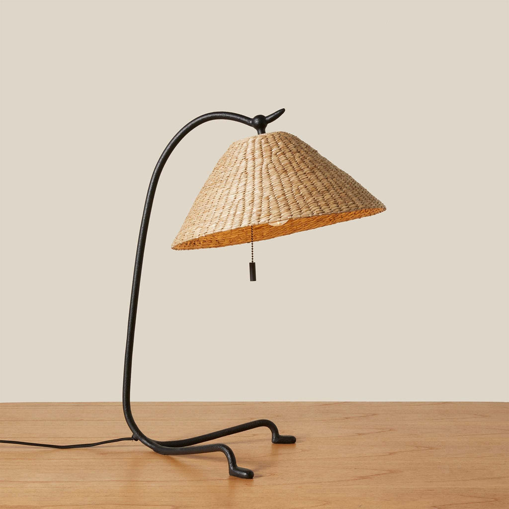 Bainbridge table lamp with wicker shade on a wooden surface against a beige background