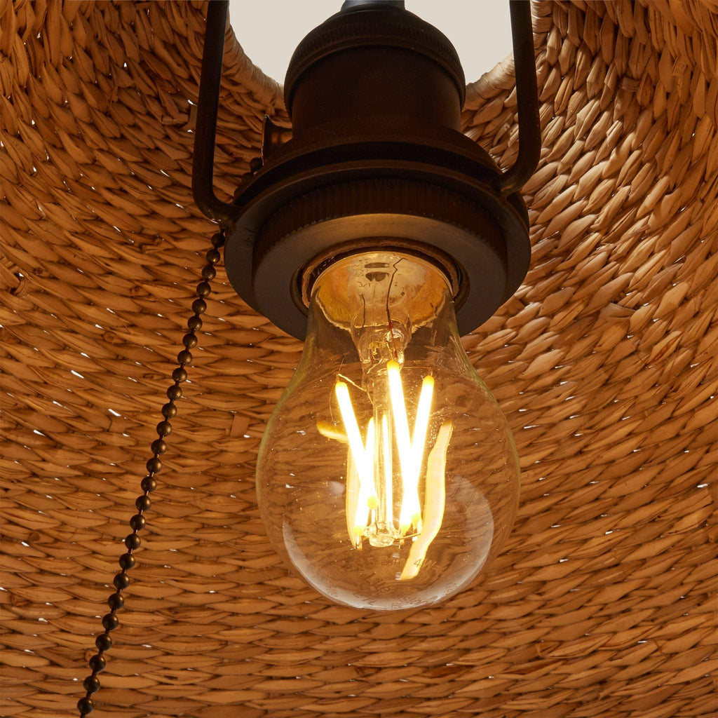 Vintage-style light bulb hanging against a woven basket background