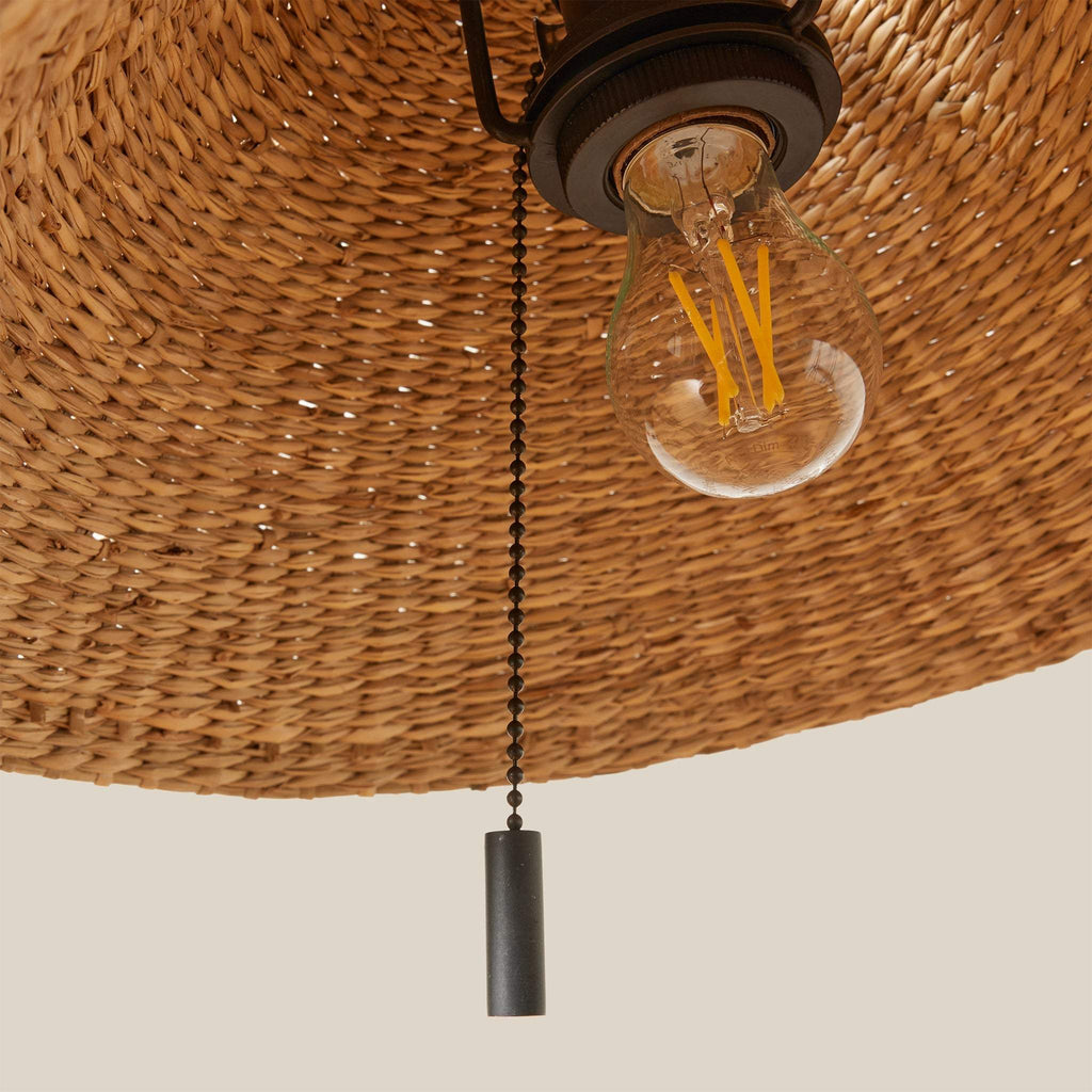 Light bulb with pull chain on a wicker lampshade of a Bainbridge table lamp