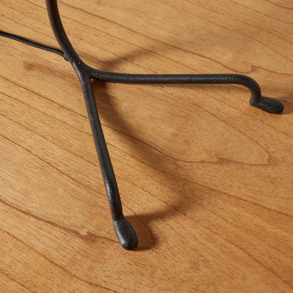Close-up of a black metal floor lamp stand on a wooden surface