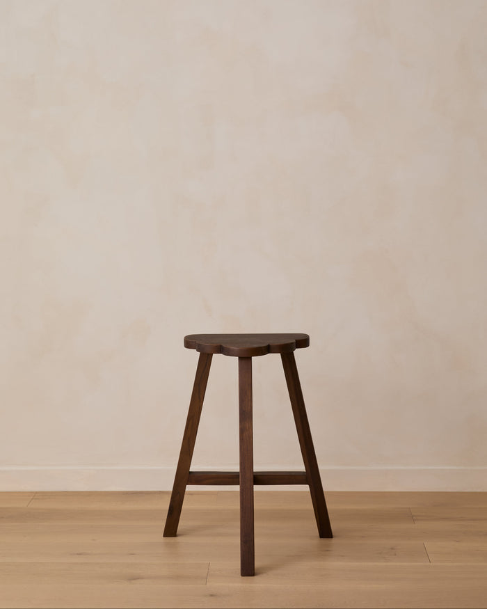 Wooden cloud shaped counter stool against a plain wall