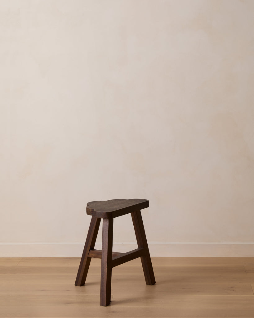 Wooden cloud-shaped accent stool against a plain beige wall