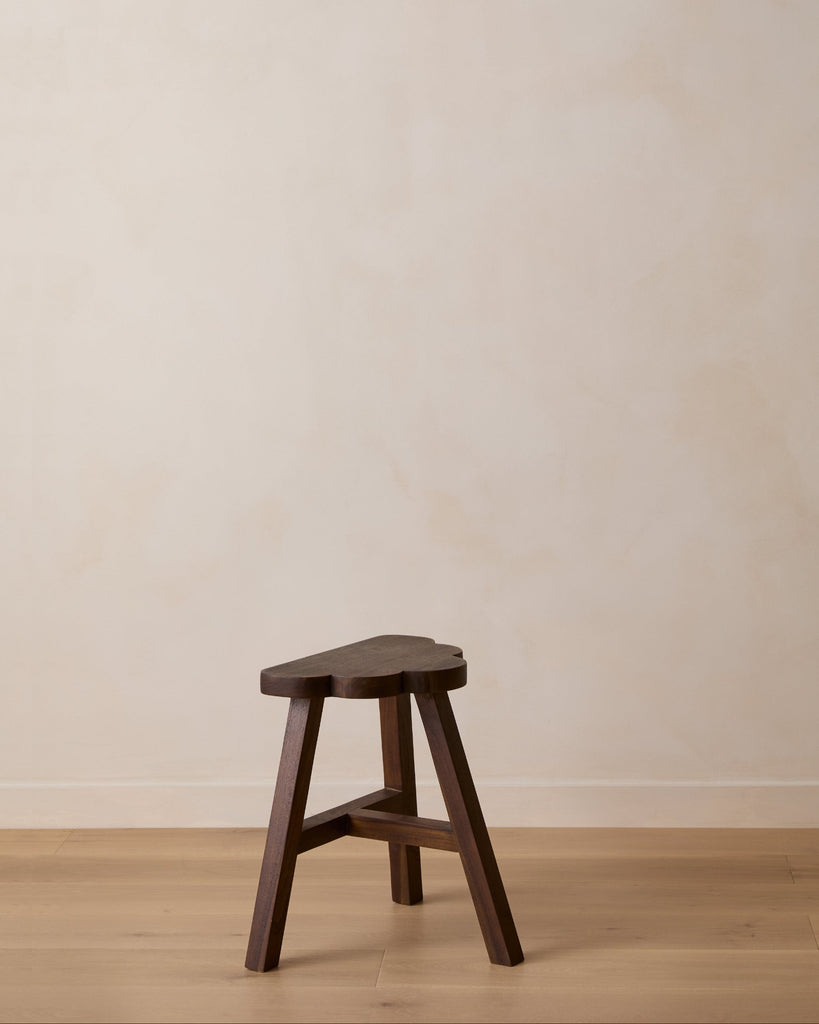 Wooden cloud-shaped accent stool against a plain wall