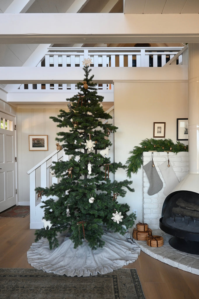 Decorated Christmas tree in a living room with a fireplace and staircase.