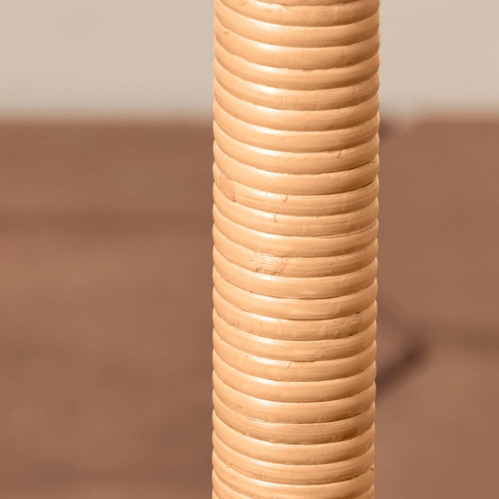 A close-up of a Delphine floor lamp set against a blurred brown and beige background.