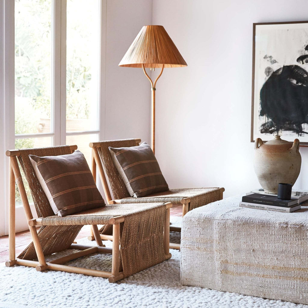 Rattan chair with cushions in a modern living room setting and Delphine floor lamp behind