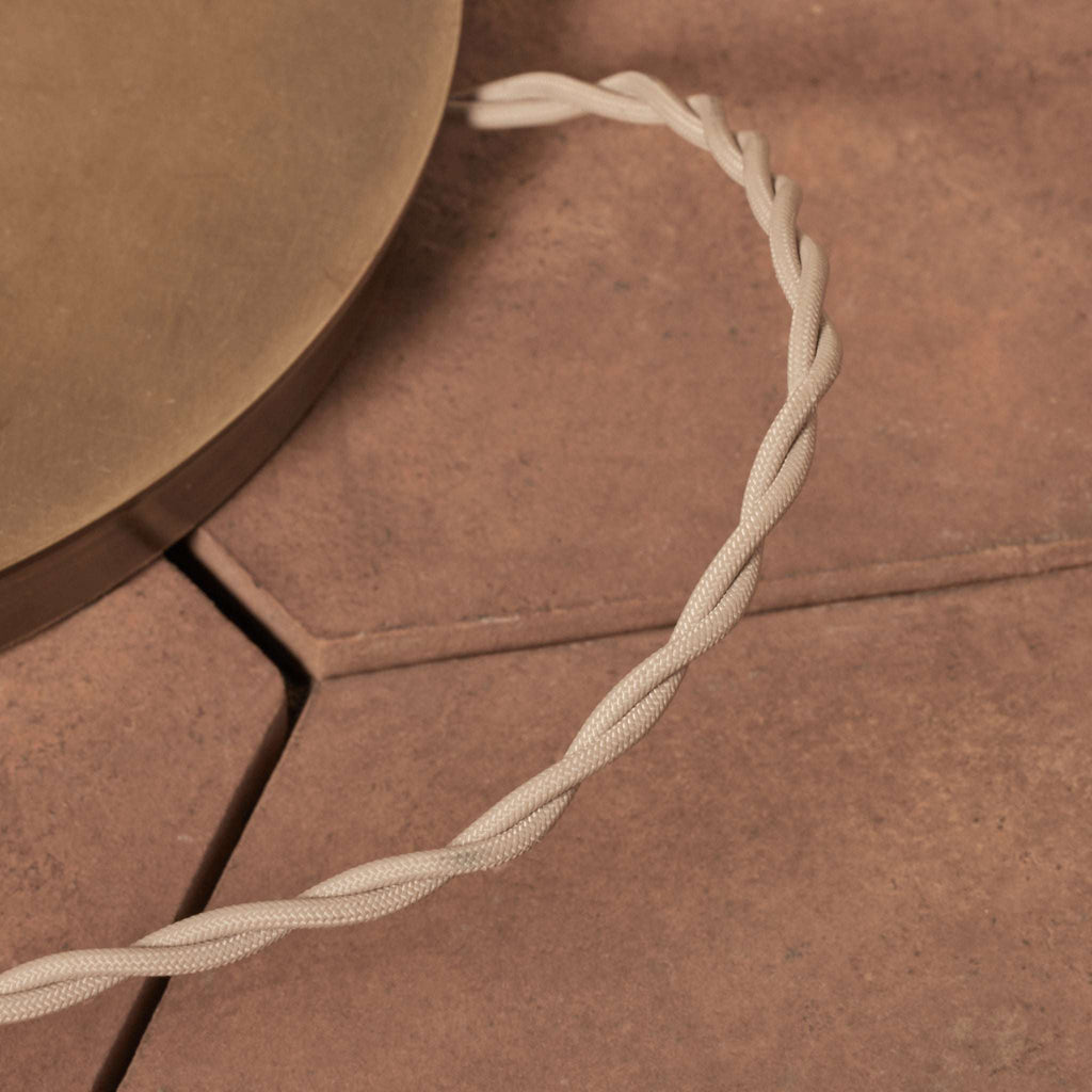 Close-up of a beige Delphine Floor lamp cord on a brown surface