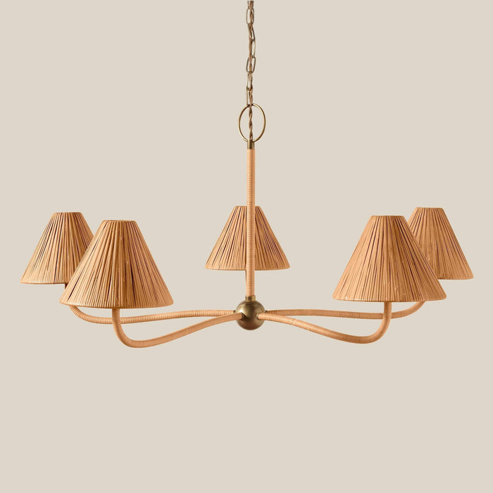 A five-light Delphine Large chandelier with curved brass-toned metal arms and pleated beige fabric shades, suspended from a chain against a solid beige background.